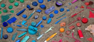 Nach Farben sortierter Müll liegt auf Sand