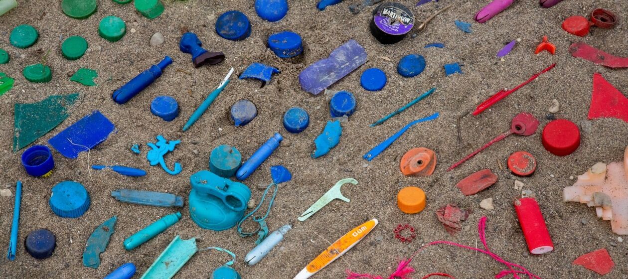 Nach Farben sortierter Müll liegt auf Sand