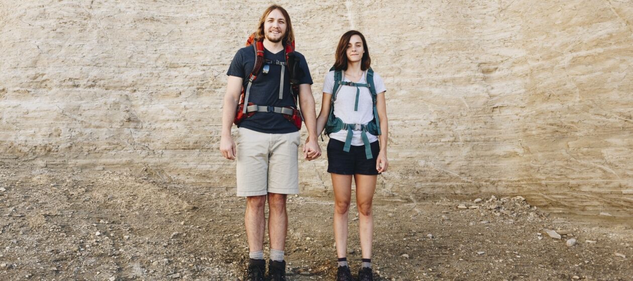 Paar mit Wanderausrüstung hält sich an den Händen