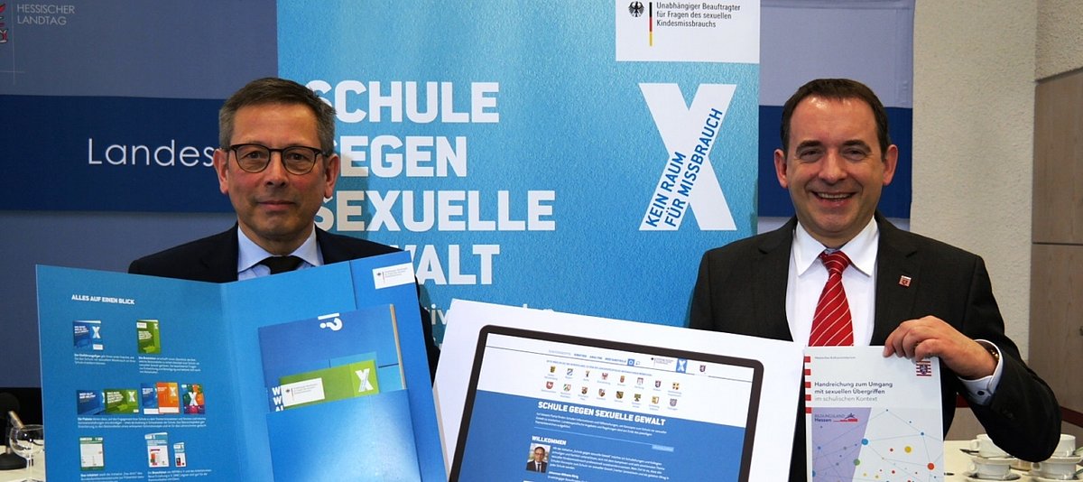 UBSKM Rörig und der hessische Kultusminister Lorz halten Informaterial der Initiative "Schule gegen sexuelle Gewalt" in den Händen
