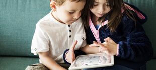 Zwei Kinder zeichnen mit den Fingern auf einem Tablet