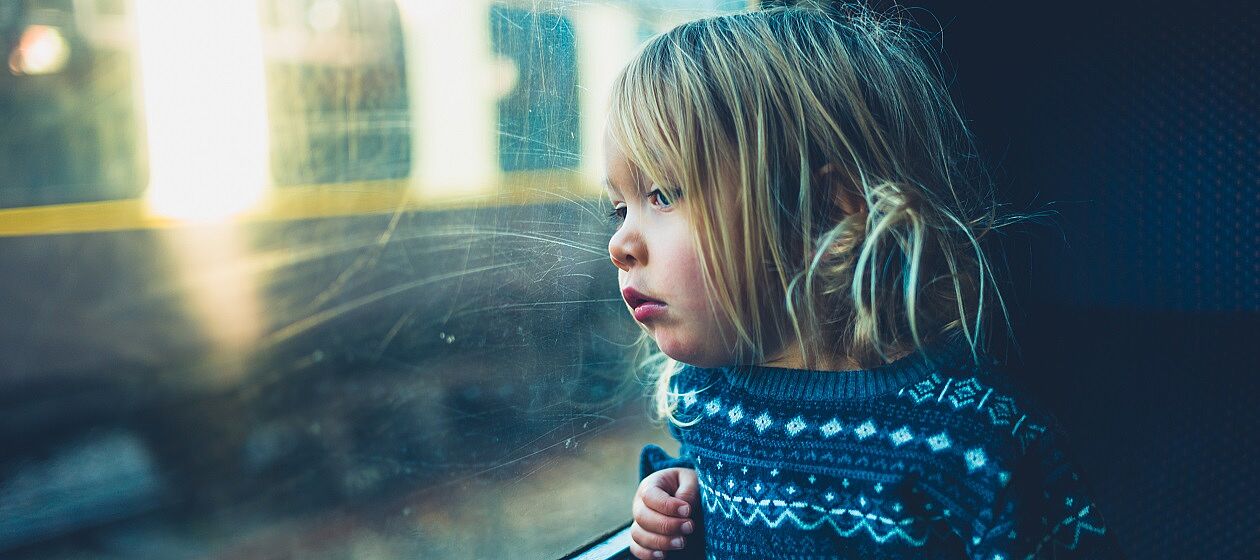 Ein Kind schaut aus einer Zugfensterscheiben