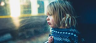 Ein Kind schaut aus einer Zugfensterscheiben