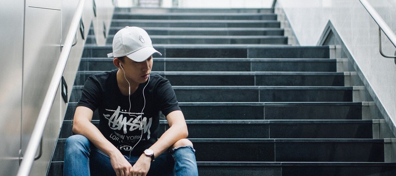 Ein Junge sitzt auf einer Treppe und hört Musik