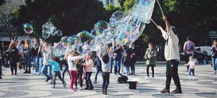 Kinder spielen mit großen Seifenblasen auf einem öffentlichen Platz