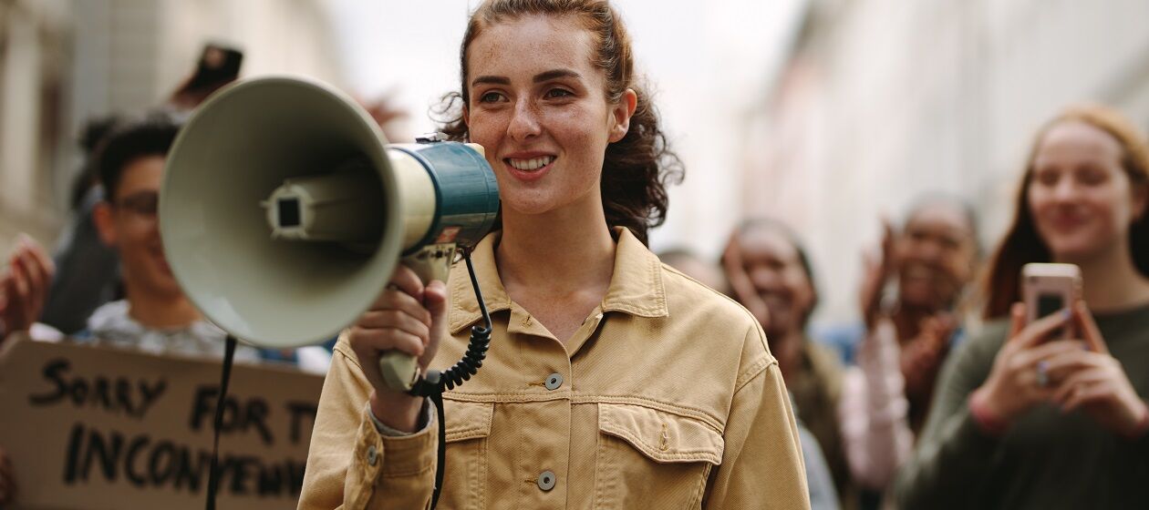Eine junge Frau mit einem Megafon läuft in einem Demonstrationszug