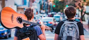 Zwei Jugendliche mit Rucksäcken und einer Gitarre