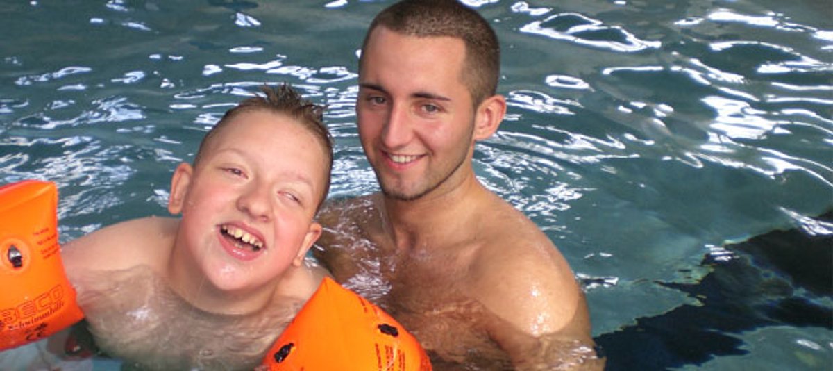Freiwilliger mit behindertem Jungen im Schwimmbecken