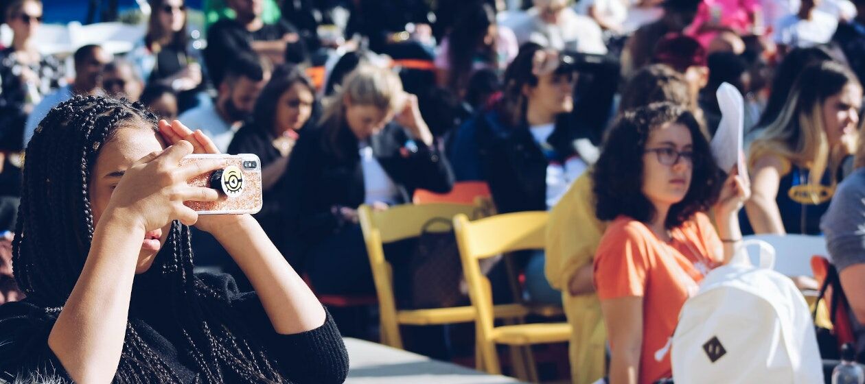 Junge Menschen bei einer Veranstaltung. Eine junge Frau macht ein Foto mit ihrer Kamera.
