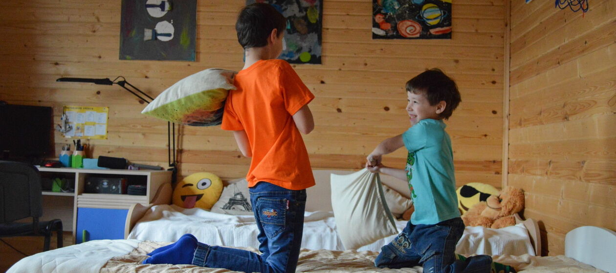 Zwei Brüder in einem Kinderzimmer bewerfen sich mit Kissen