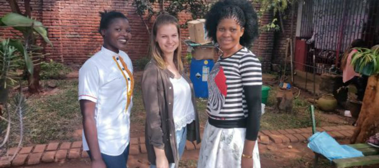 Drei junge Frauen unterschiedlicher Herkunft stehen zusammen im Freien und lächeln