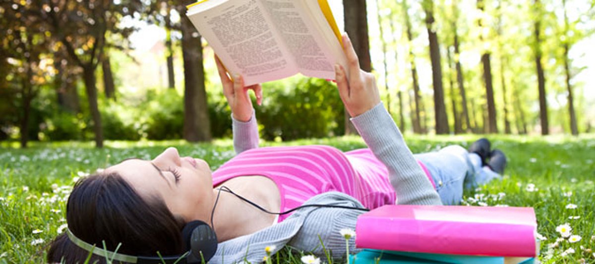 Ein junge Frau liegt auf dem Rasen und liest