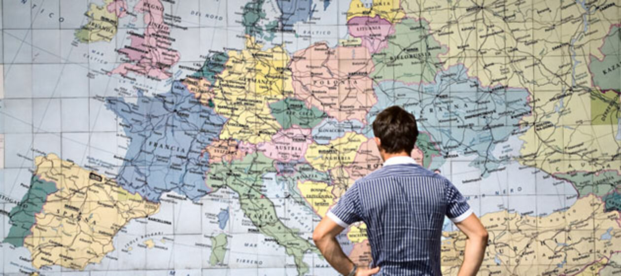 Ein junger Mann steht vor einer Europa-Karte