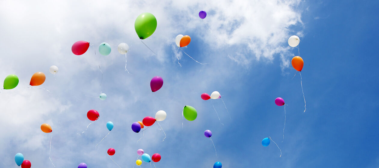 Viel bunte Luftballons steigen in blauen Himmel mit Wolken