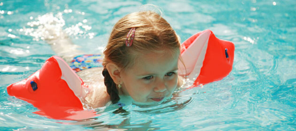 Ein Mädchen schwimmt mit Schwimmflügeln