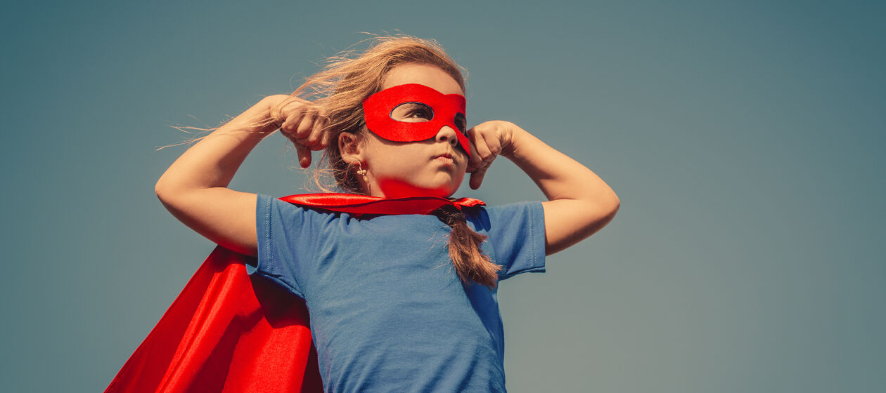 Mädchen ist als Superheld mit rotem Umhang und roter Maske verkleidet