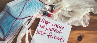 "Keep calm and protect your friends" Notiz mit Maske und Handschuhen auf einem Tisch