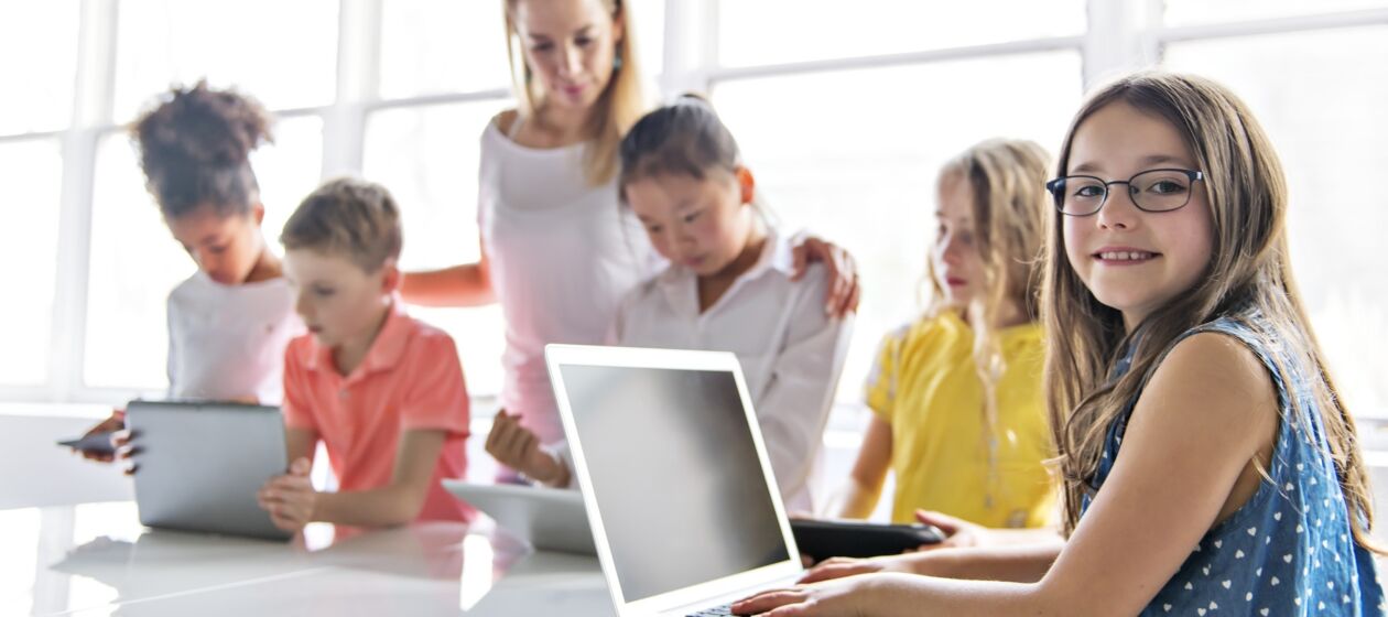 Schulkinder sitzen an Laptops und lernen