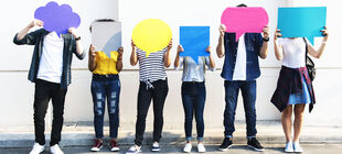 Sechs junge Menschen stehen vor einer Mauer und halten sich bunte Sprechblasen vor ihr Gesicht.