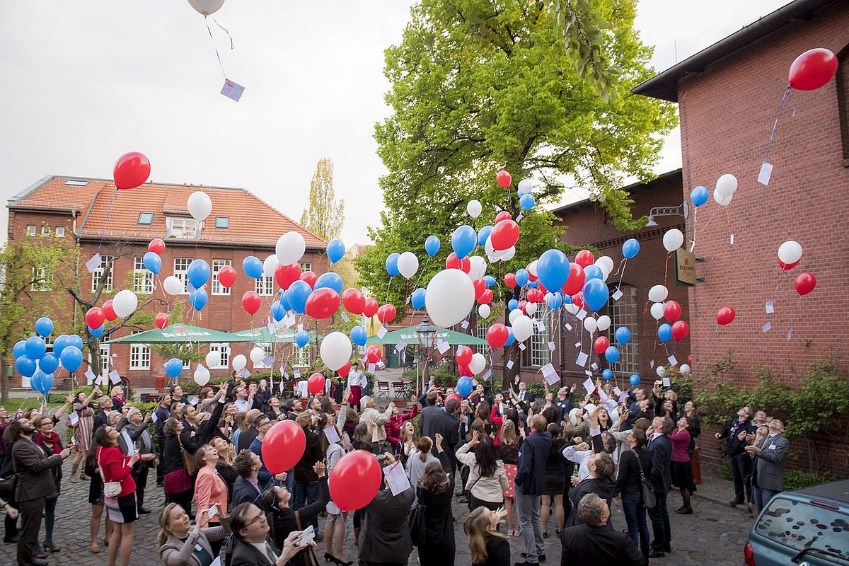 Die Teilnehmer der Jubiläumsveranstaltung lassen viele bunte Luftballons in den Himmel steigen. 