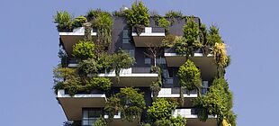 Ein Haus auf dessen Balkonen und Dach sehr viele Pflanzen und Sträucher gefplanzt sind