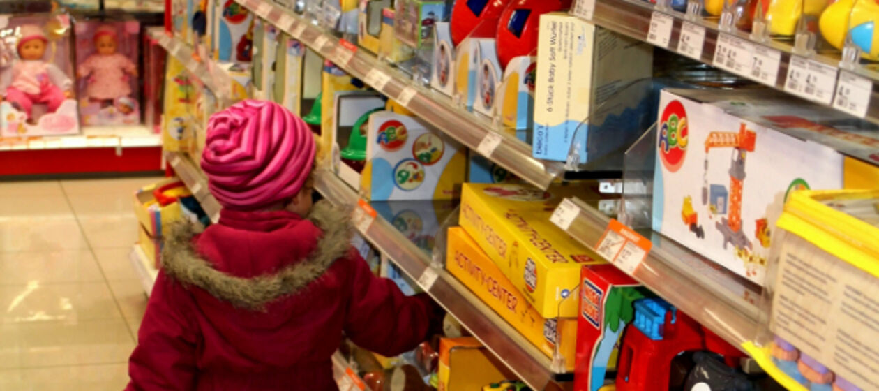 Ein Kleinkind geht durch Regale mit Spielwaren