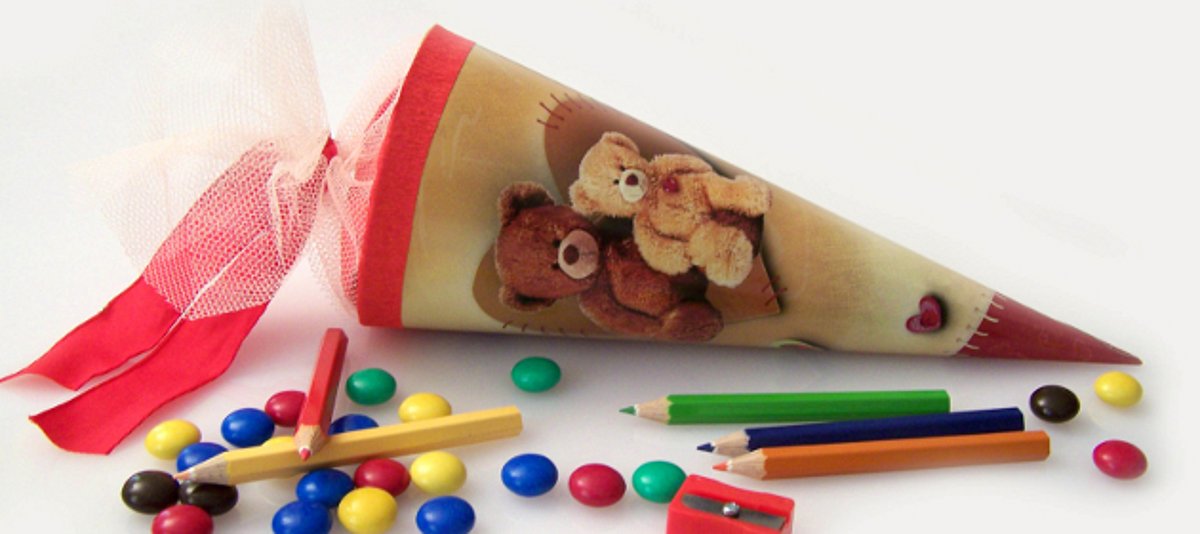 Das Bild zeigt eine Schultüte, Buntstifte und Süßigkeiten.