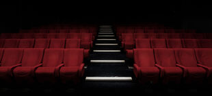 Ein abgedunkelter, leerer Kinosaal mit roten Sesseln