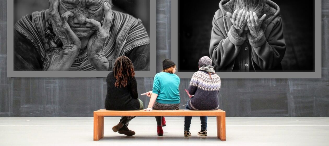 Drei Personen sitzen in einem Museum auf einer Bank und schauen auf sehr große an der Wand hängende Fotografien