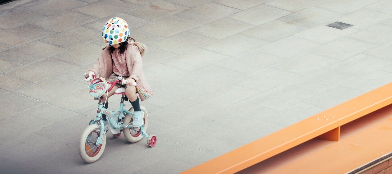Ein Mädchen fährt auf einem Fahrrad mit Stützrädern