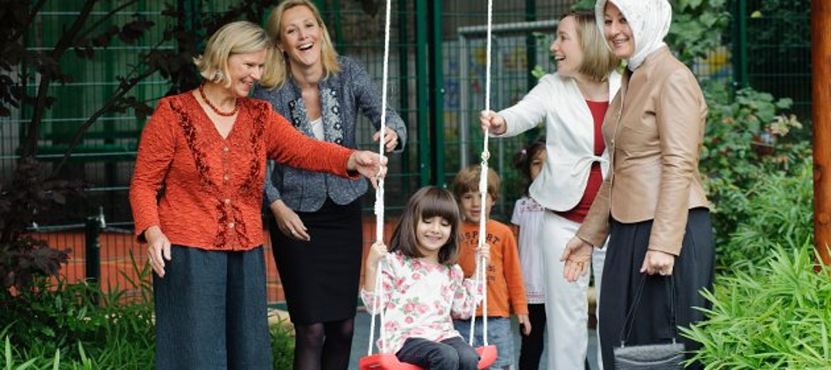 Bundesfamilienministerin Schröder und DKJS-Schirmherrin Bettina Wulff geben Kind Schwung beim Schaukeln