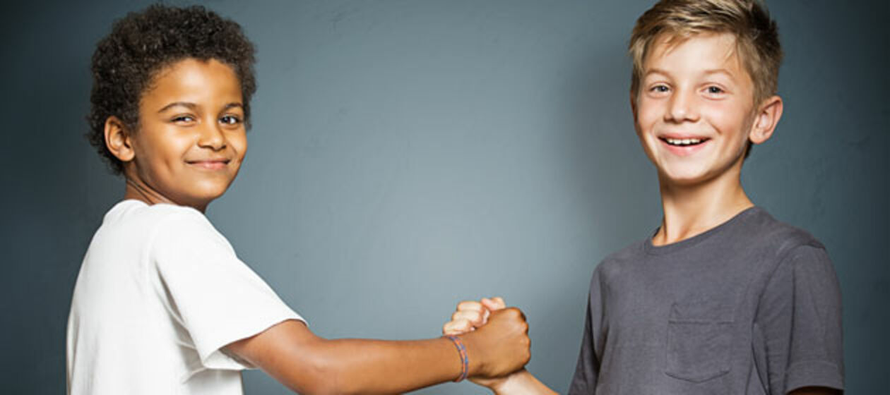 Ein farbiger und ein weißer Junge geben sich die Hand.