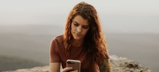 Eine junge Frau schaut auf ihr Smartphone
