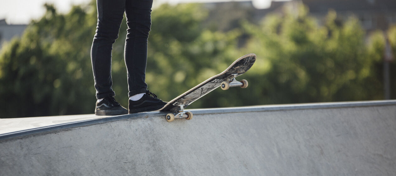 Person mit Skateboard am Rand einer Halfpipe