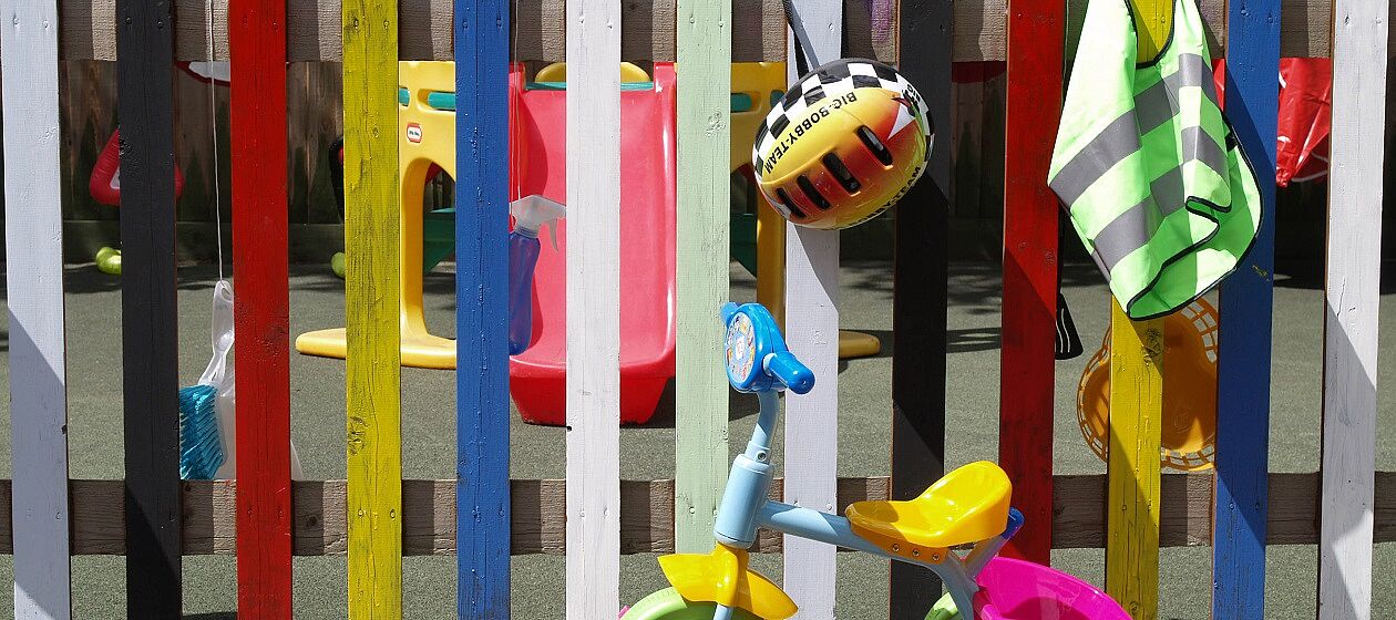 Der Zaun eines Kindergartens ist bunt bemalt.