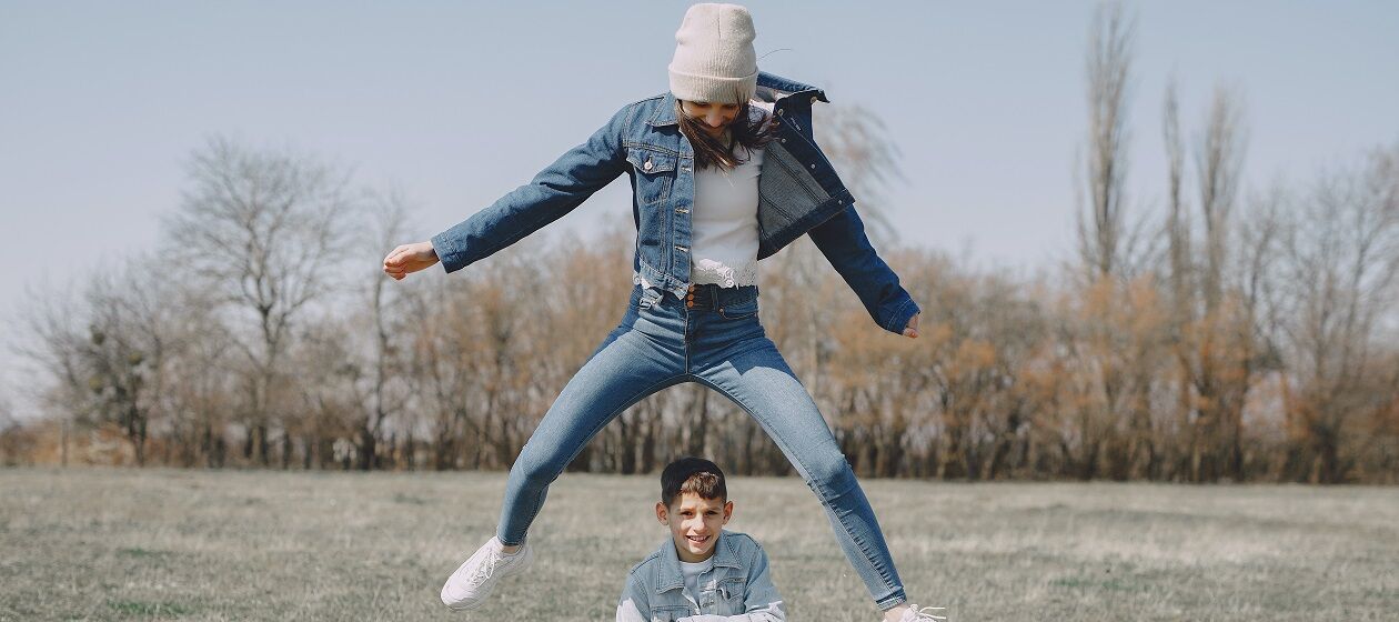 Ein Mädchen springt in die Luft, ein Junge sitzt auf dem Boden