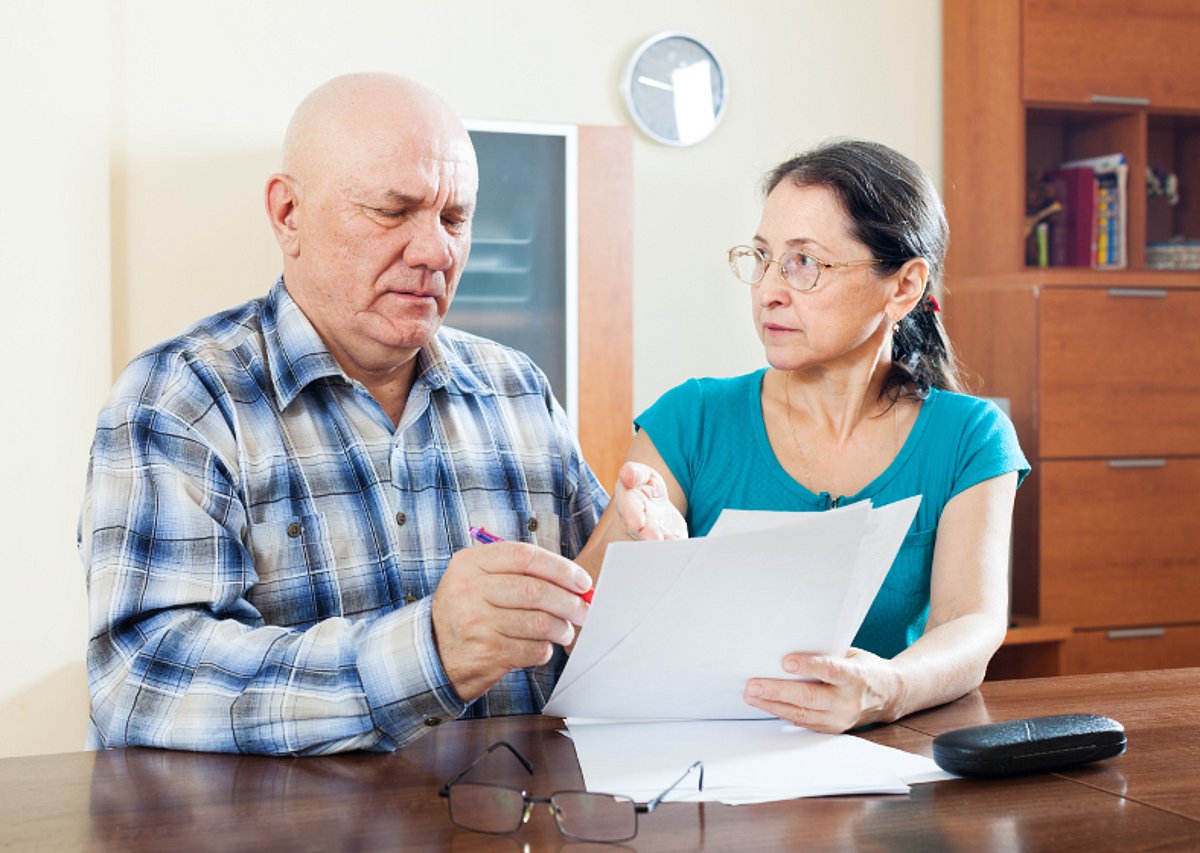 Ein älteres Ehepaar schaut sich besorgt Unterlagen an.