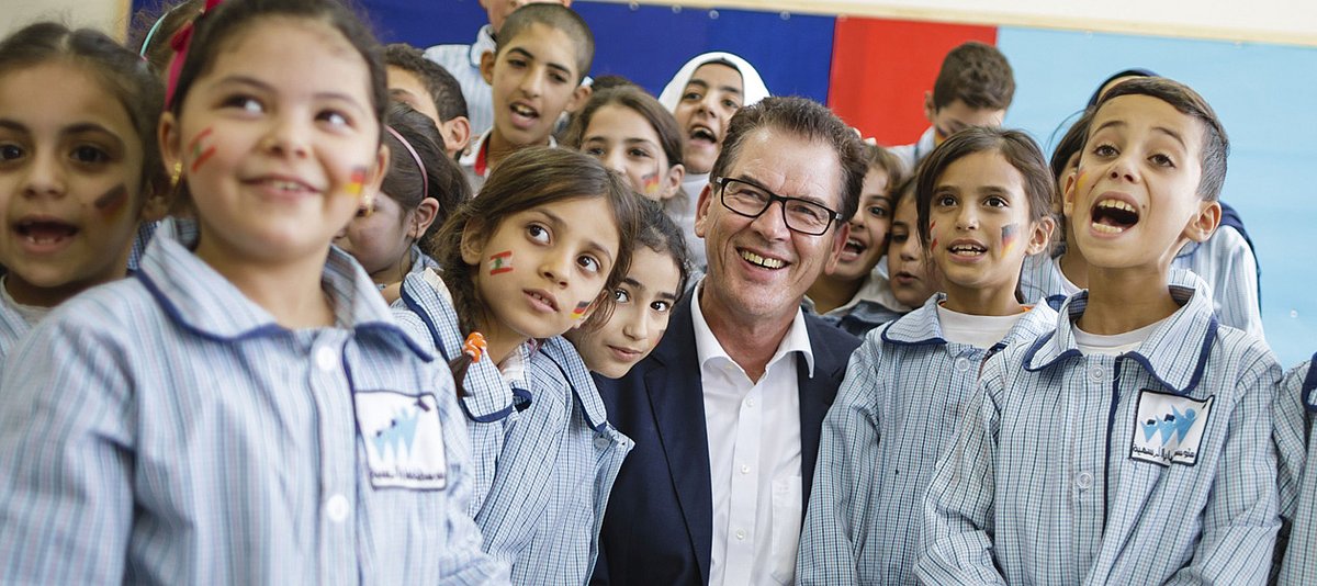 Entwicklungsminister Müller steht mit einer Gruppe von Jugendlichen in einem Klassenraum in einer Schule im Libanon. 