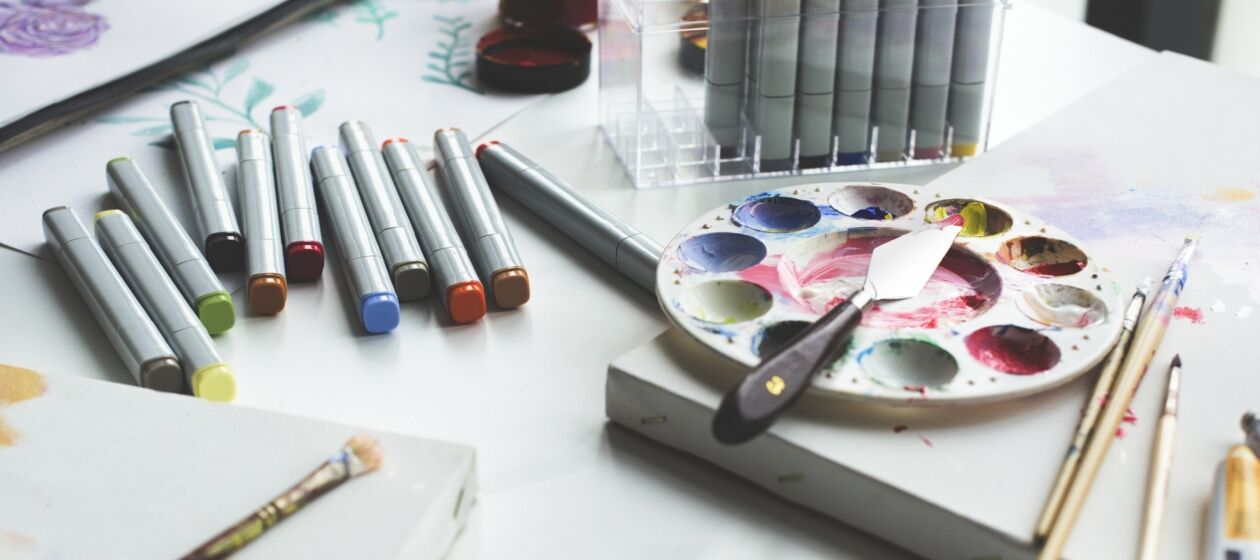 Stifte, Farben, Leinwände und andere Malutensilien liegen auf einem Tisch