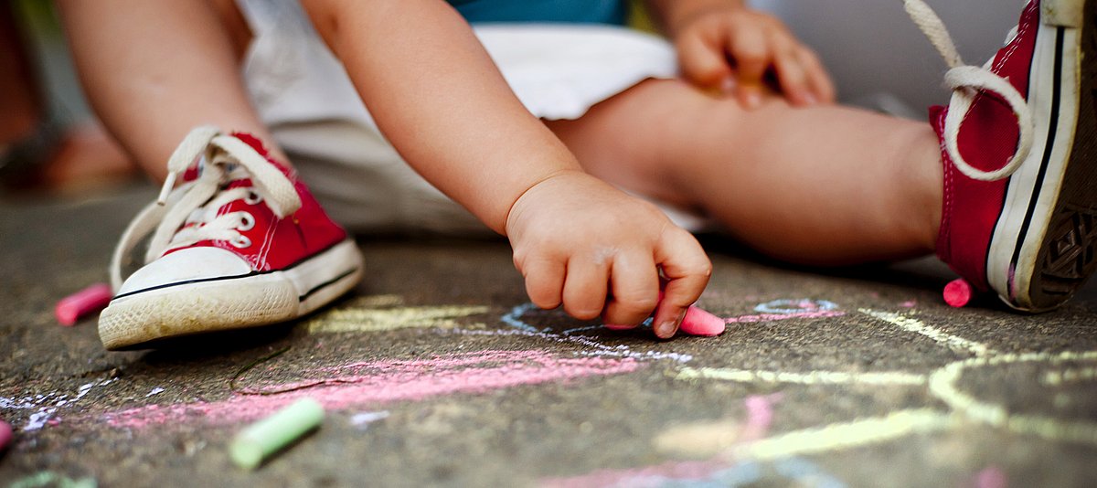 Kind malt mit Kreide auf der Straße