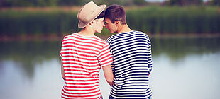 Zwei verliebte homosexuelle Männer am See schauen sich in die Augen.