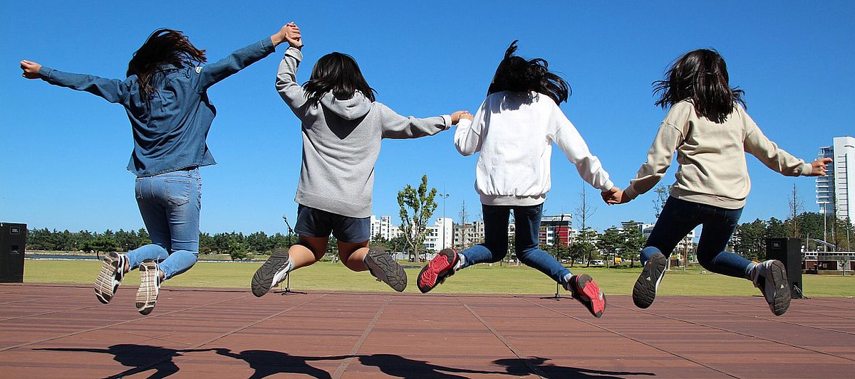 Vier Mädchen springen auf einem Sportplatz.