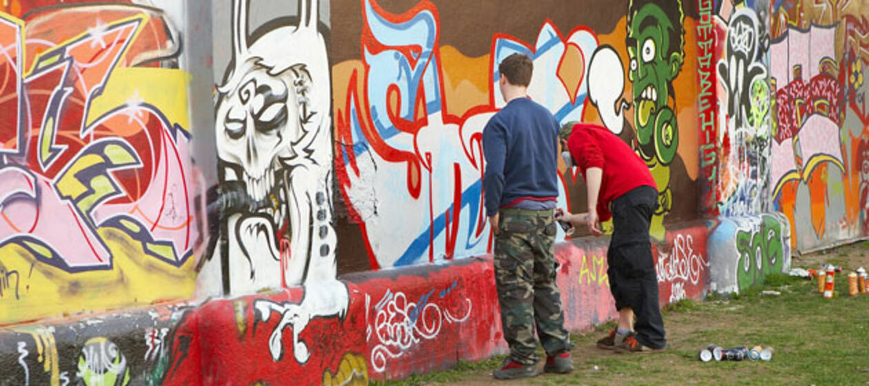 Zwei jugendliche Sprayer vor Graffiti-Wall