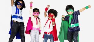 Vier maskierte Kinder mit farbigen Umhänge strecken kraftvoll ihre Arme nach oben