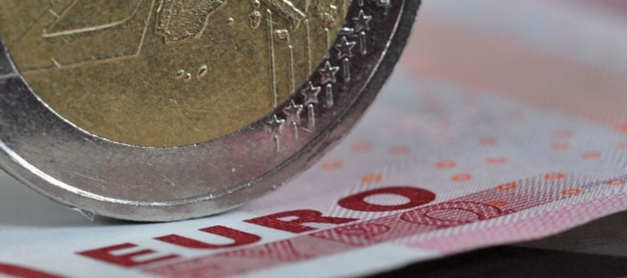 Eine Zwei-Euro Münze steht auf einem 10-Euro Schein