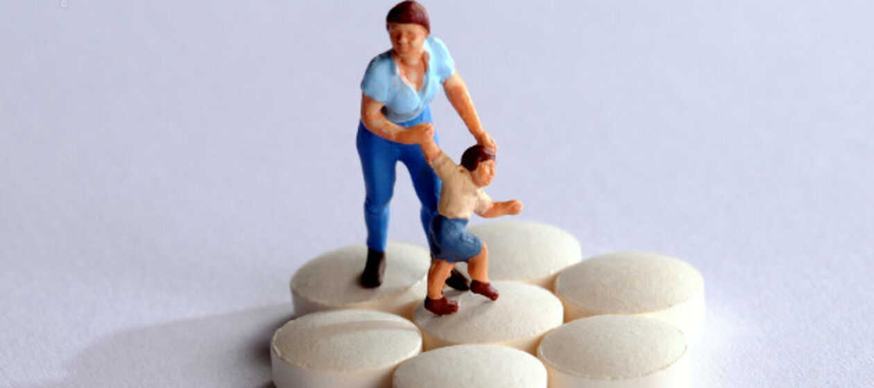 Plastik-Figur: Mutter mit Kind auf Tablettenhaufen