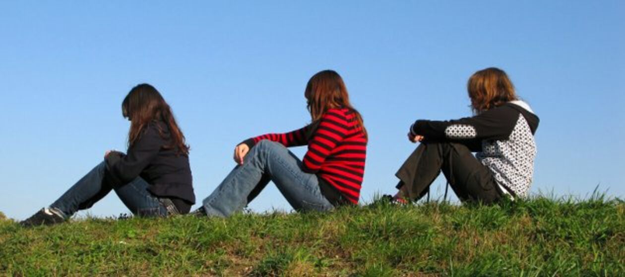 Drei Mädchen sitzen auf Wiese