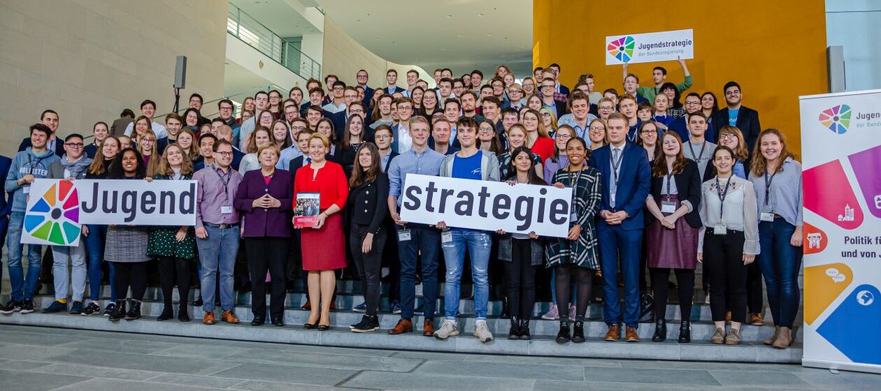 Kanzlerin Merkel und Bundesministerin Giffey auf einem Gruppenbild zusammen mit vielen Jugendlichen